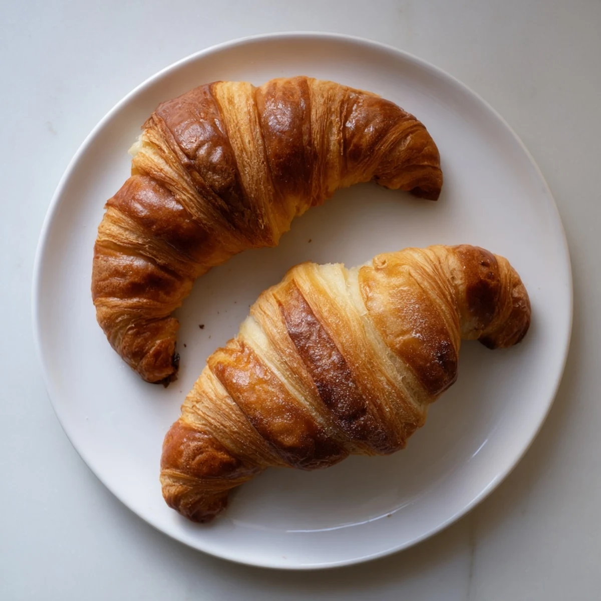 Buttery flaky homemade croissants served on a white plate for breakfast or brunch