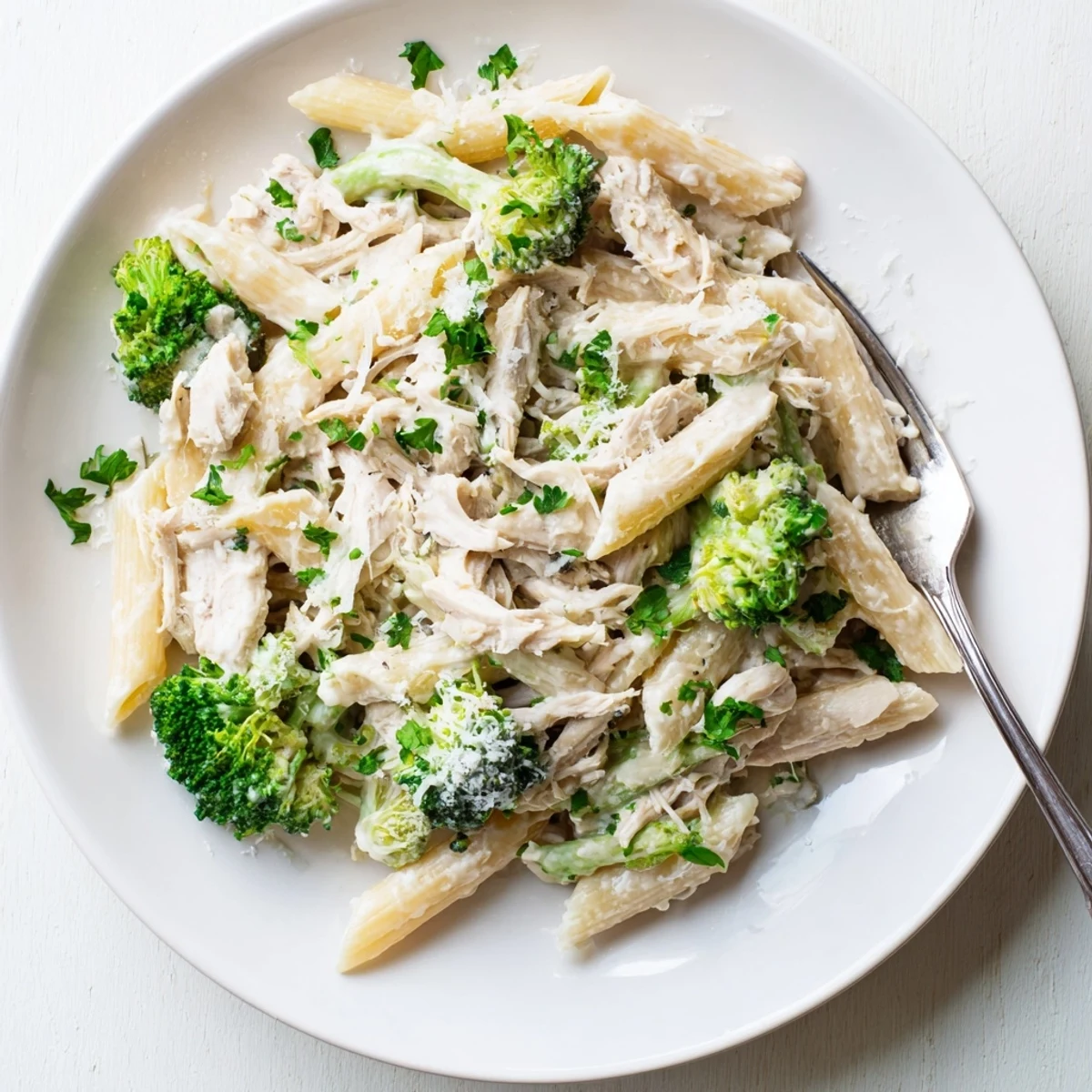 Twisted penne pasta tossed with shredded rotisserie chicken and tender broccoli florets in a rich garlic cheese sauce