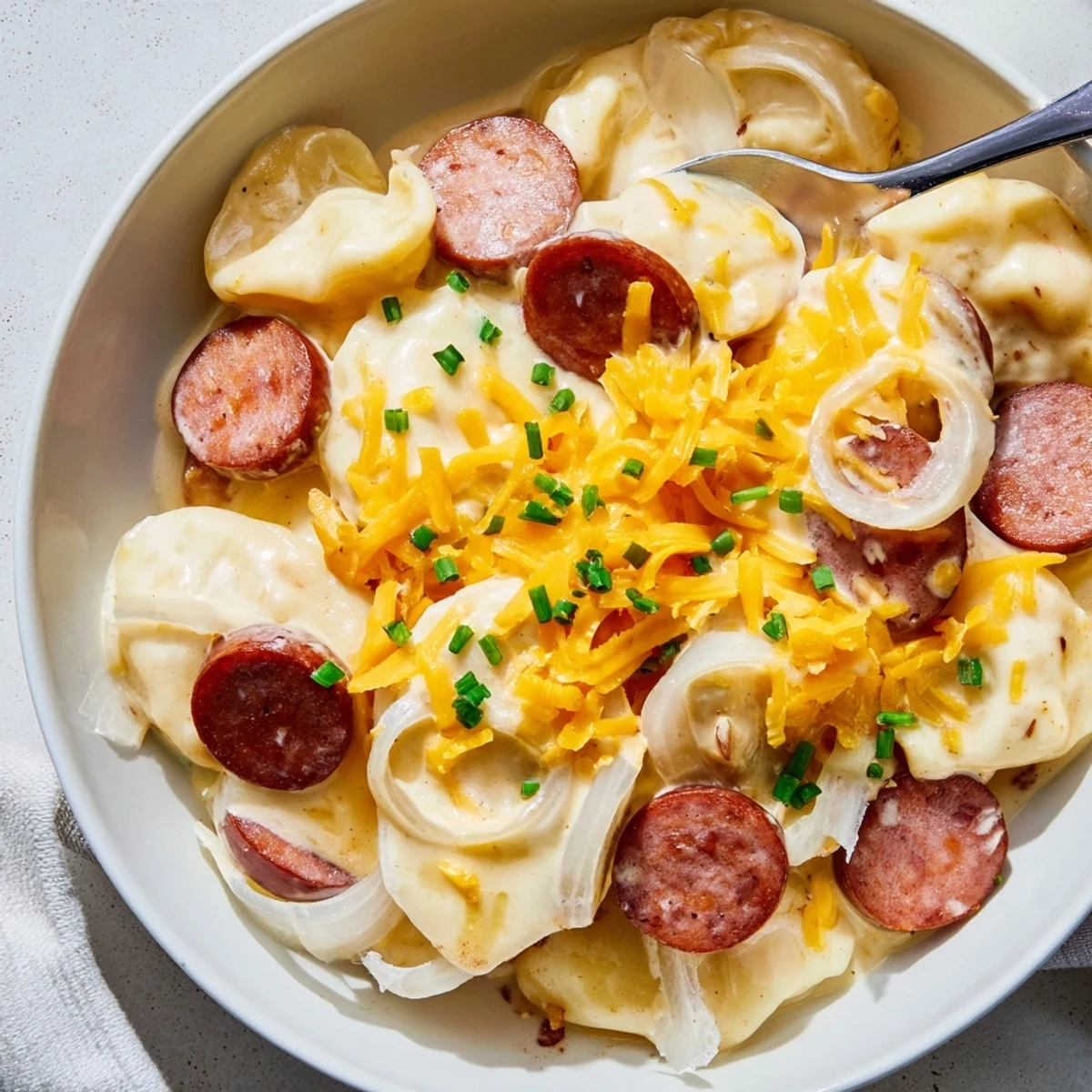 Golden brown Crock Pot Pierogi Casserole with melted cheddar and sliced kielbasa bubbling in slow cooker