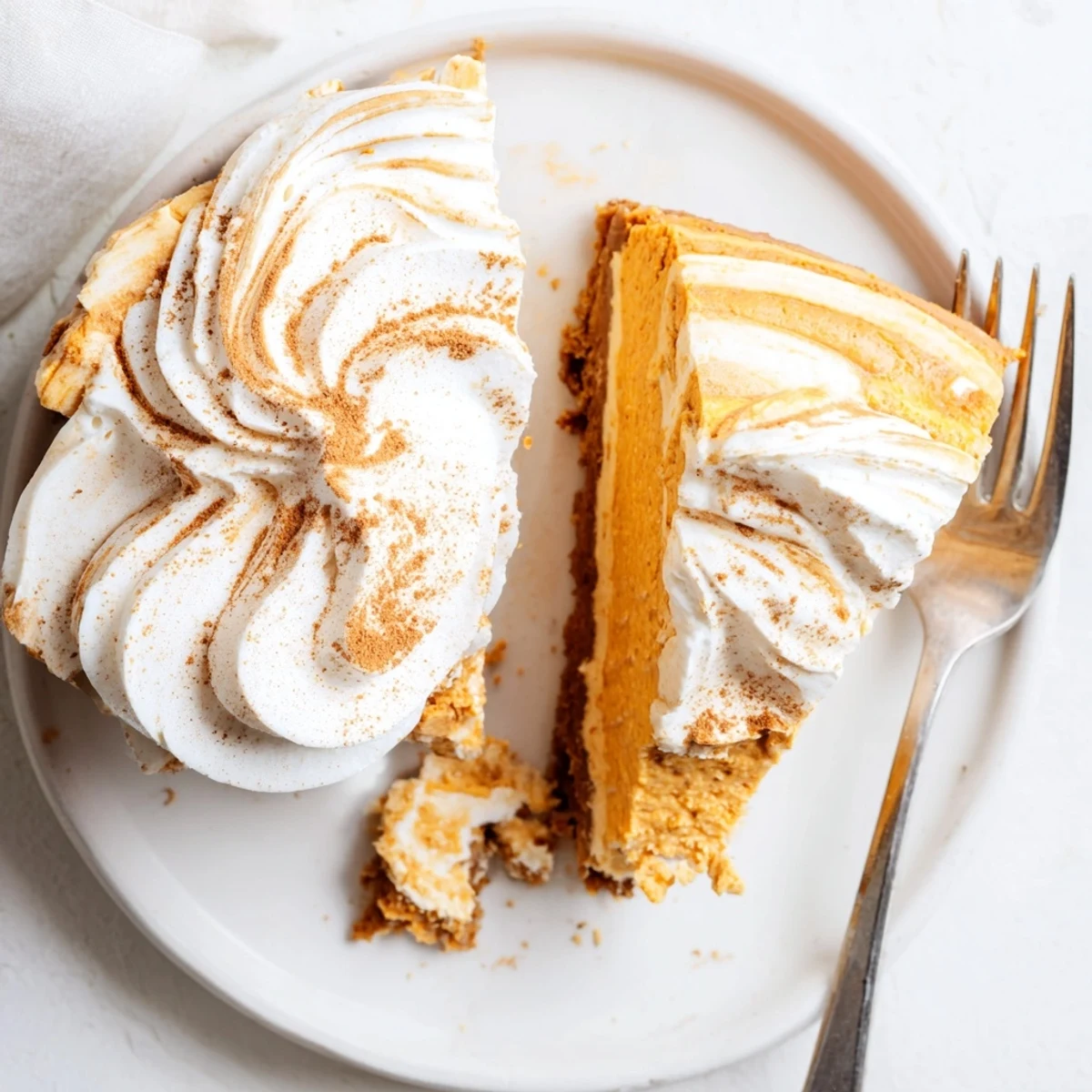 Creamy pumpkin spice Christmas cheesecake topped with fluffy whipped cream and cinnamon dusting