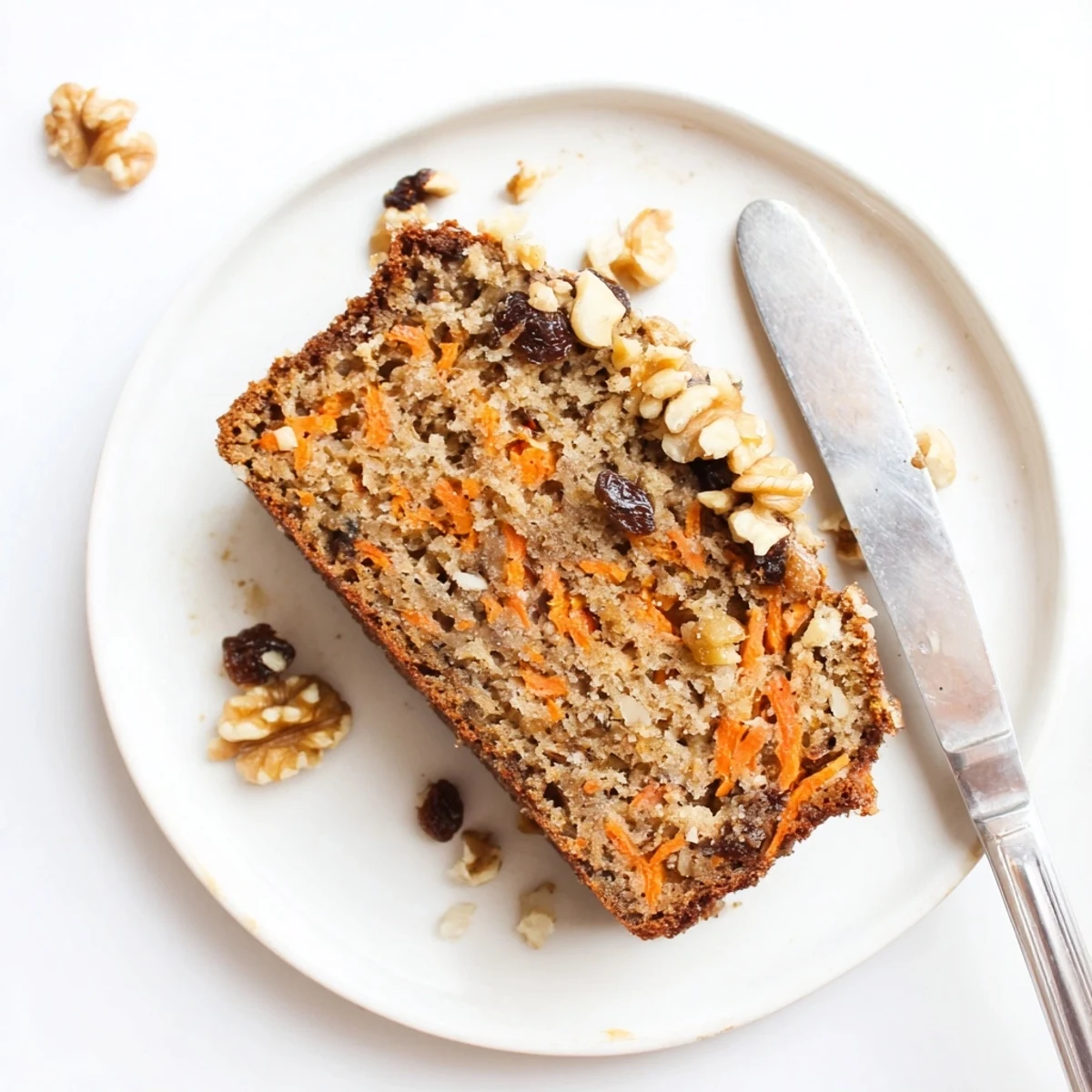 Moist carrot cake banana bread loaf topped with chopped walnuts on a wooden board