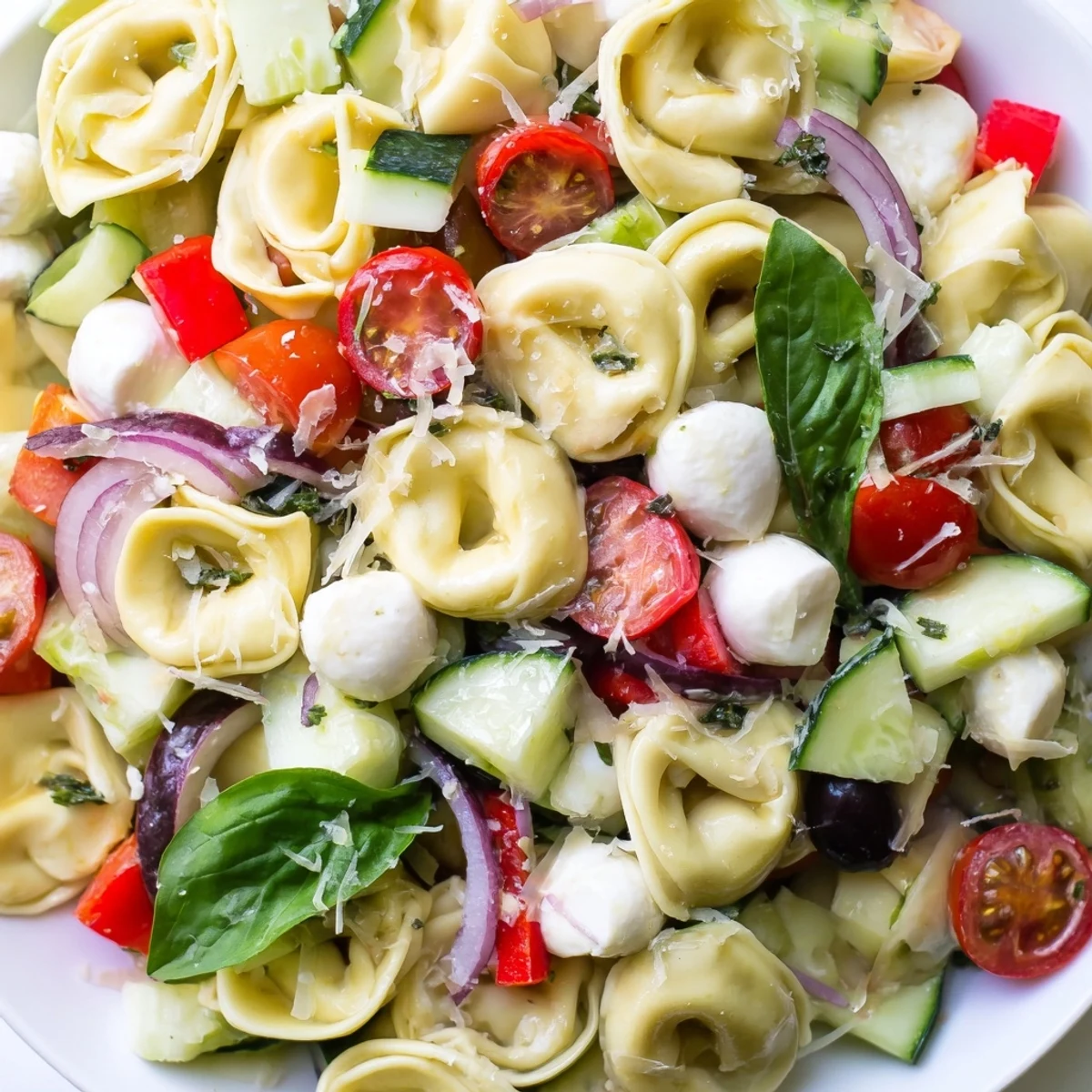 Creamy cheese tortellini salad tossed with crisp vegetables and zesty herbs for picnics