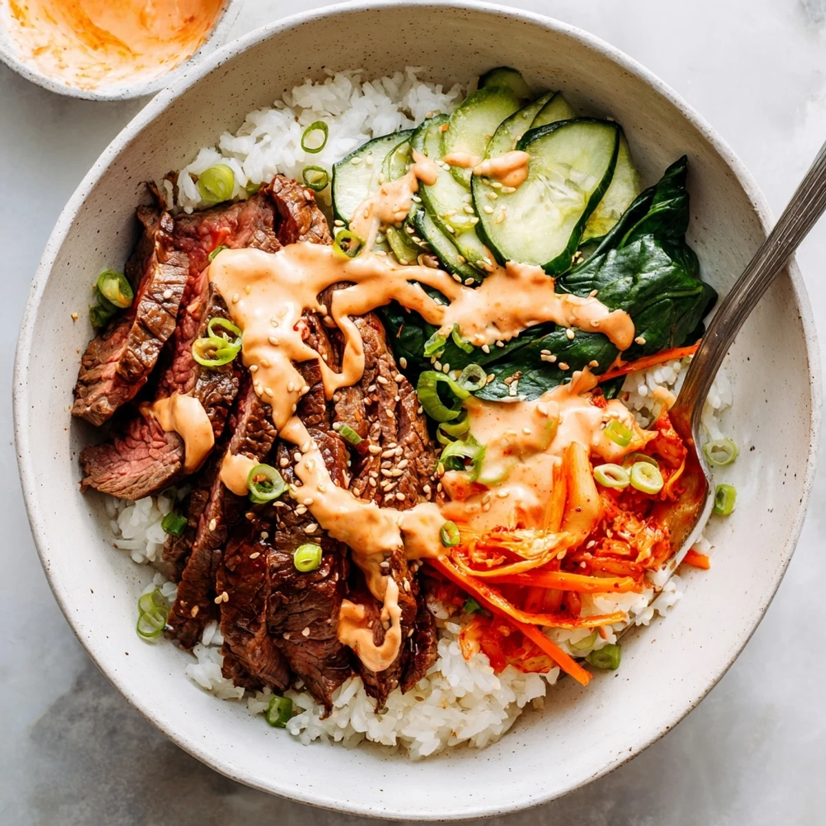 Sizzling marinated beef nestled on warm rice with shredded carrots and spicy mayo in Korean BBQ steak rice bowls