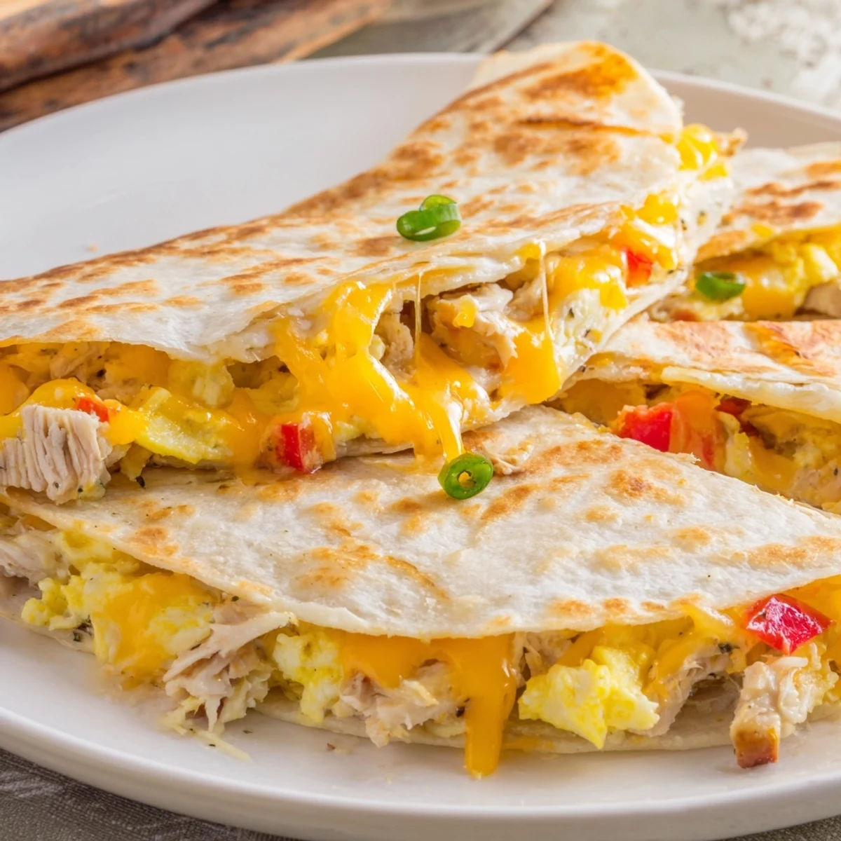 Savory Chicken Breakfast Quesadilla sliced into wedges, served with avocado and salsa.