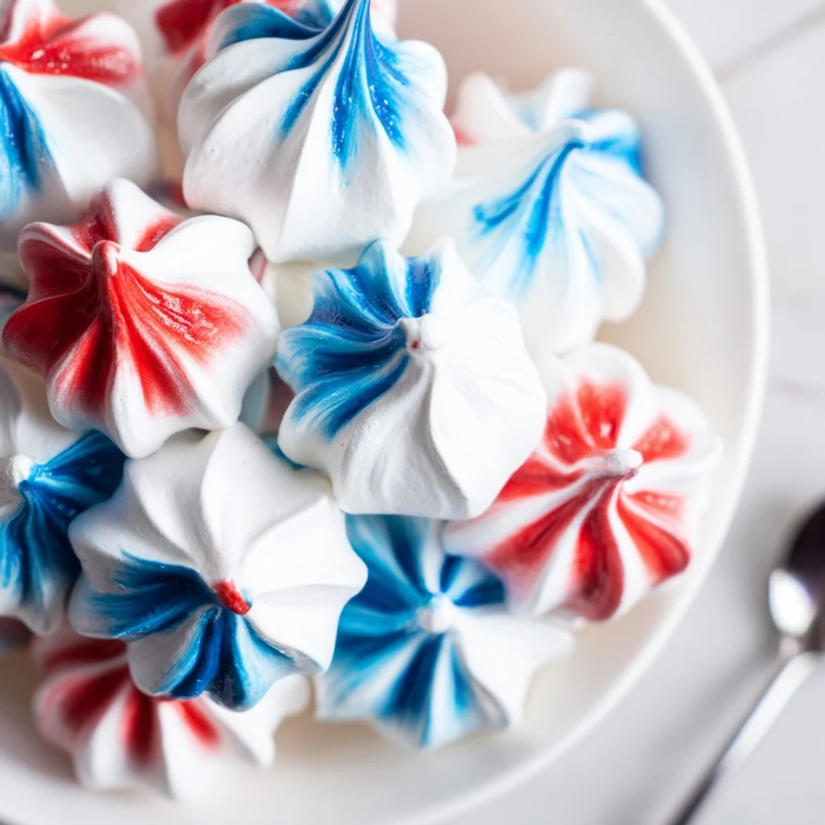 Patriotic Meringue Kisses glossy red, white, blue swirls on parchment lined baking sheet