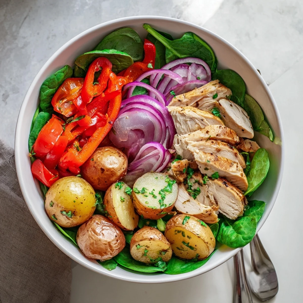 Lean grilled chicken paired with oven-roasted potatoes and crisp vegetables garnished with fresh parsley in a gluten-free dinner bowl