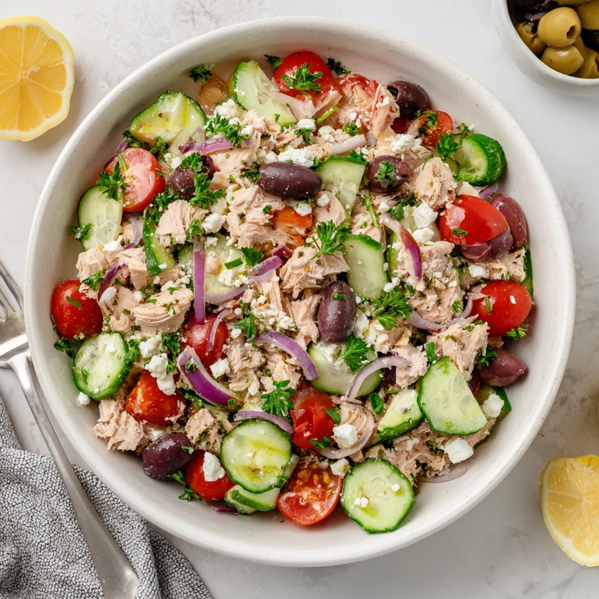 Vibrant Mediterranean tuna salad served in white bowl with red bell pepper, Kalamata olives, fresh parsley, and light citrus vinaigrette.