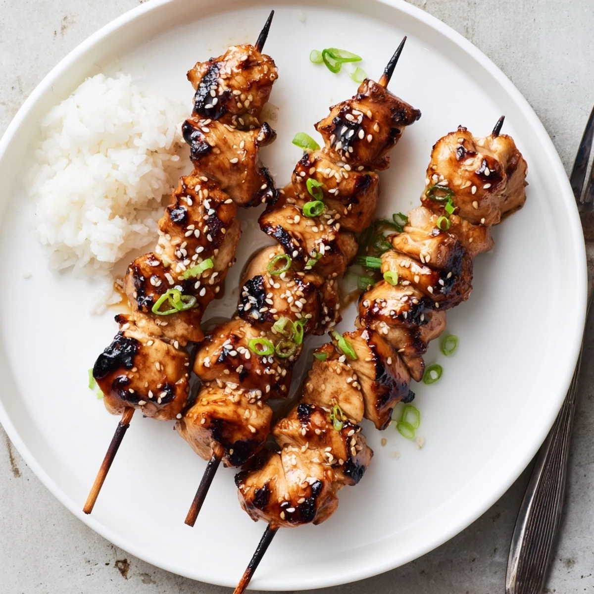 Teriyaki Chicken Skewers glistening with sticky glaze, toasted sesame, scallions, steaming rice.