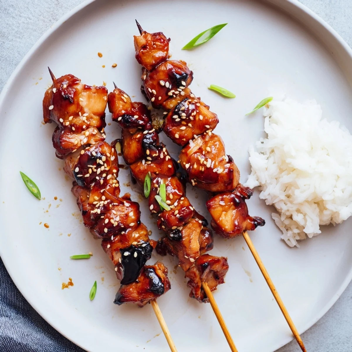 Savory Teriyaki Chicken Skewers brushed with warmed glaze, sesame seeds, green onions.