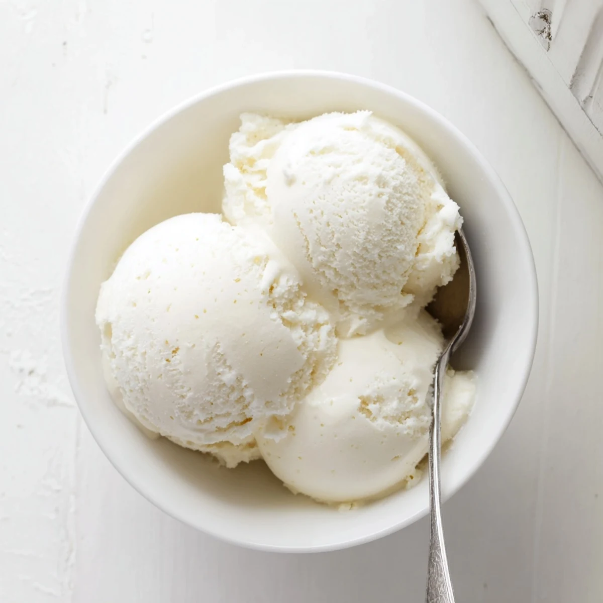 Creamy homemade vanilla ice cream scoop in a glass bowl with fresh berries garnish