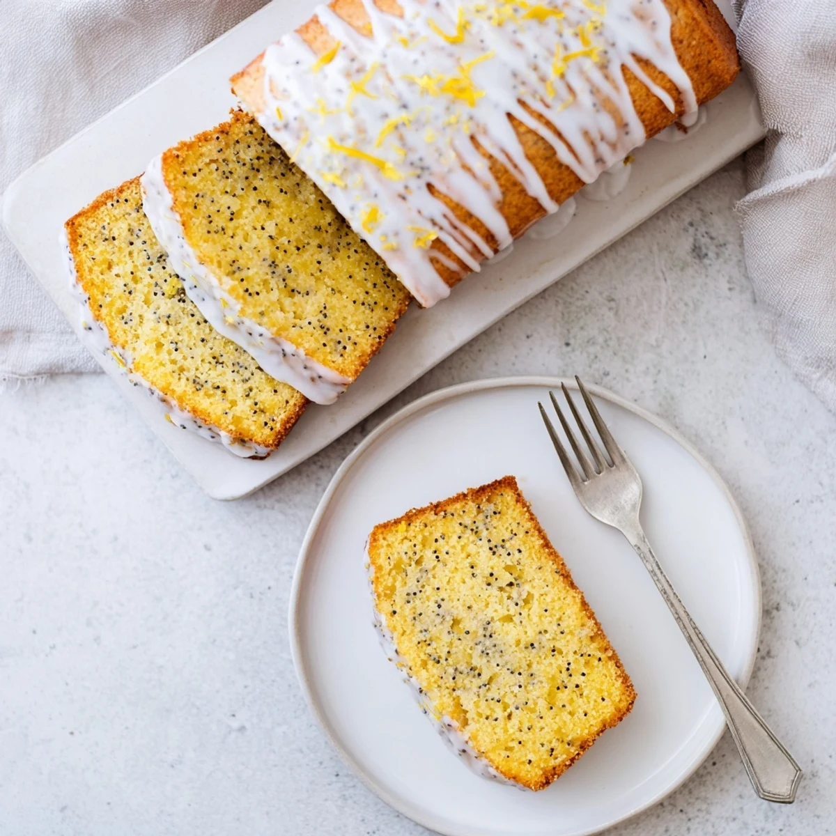 Freshly baked lemon poppy seed bread with sweet icing on a white serving plate