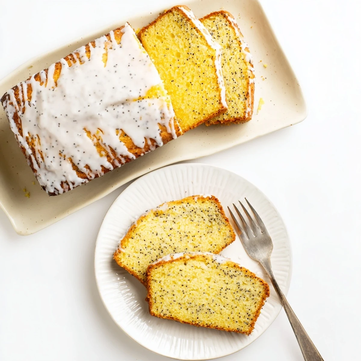 Moist lemon poppy seed cake slice topped with tangy glaze and fresh lemon zest garnish