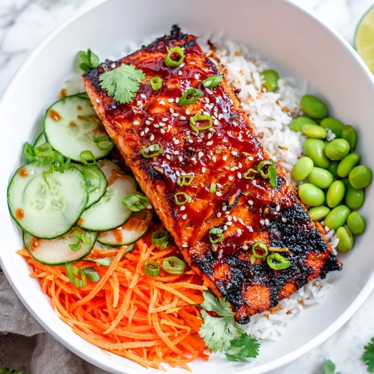 Spicy sriracha honey glazed salmon bowls drizzled with sticky sauce alongside crunchy cucumber and carrots