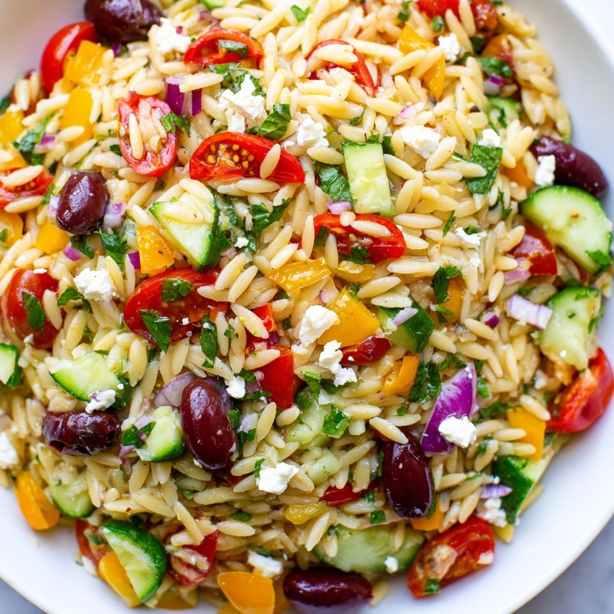 A bright bowl of Mediterranean Orzo Pasta Salad served at a sunny summer picnic table