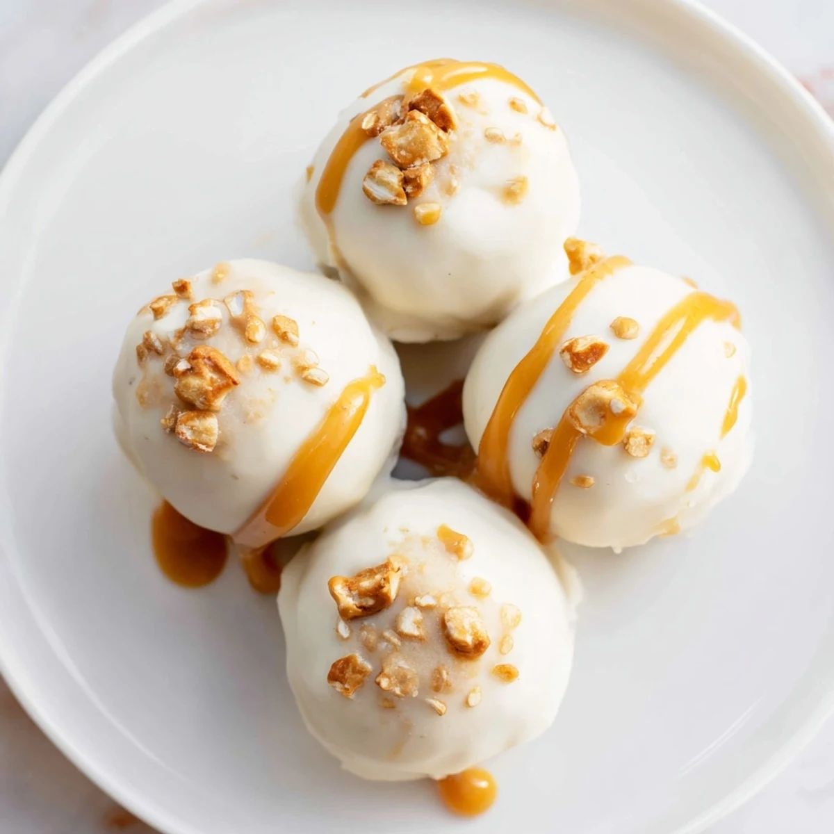Golden salted caramel pretzel cheesecake balls drizzled with caramel on a rustic tray