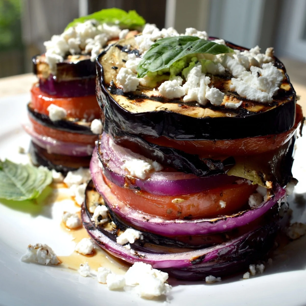Charred grilled tomato eggplant slices arranged on a rustic plate glistening with balsamic marinade