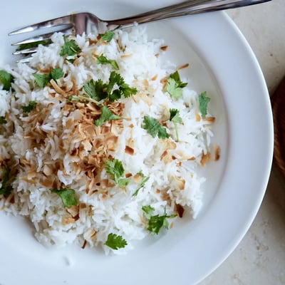 Steaming bowl of coconut rice served alongside a rich Thai curry